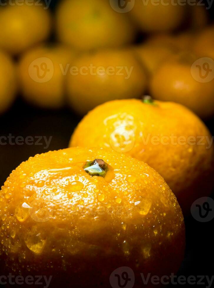 goutte d'eau sur une surface brillante de fraîcheur orange sur fond noir photo