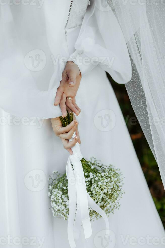 élégant bouquet de le la mariée. détient derrière le dos. proche en haut. une bouquet de gypsophile. sur une blanc Contexte. photo