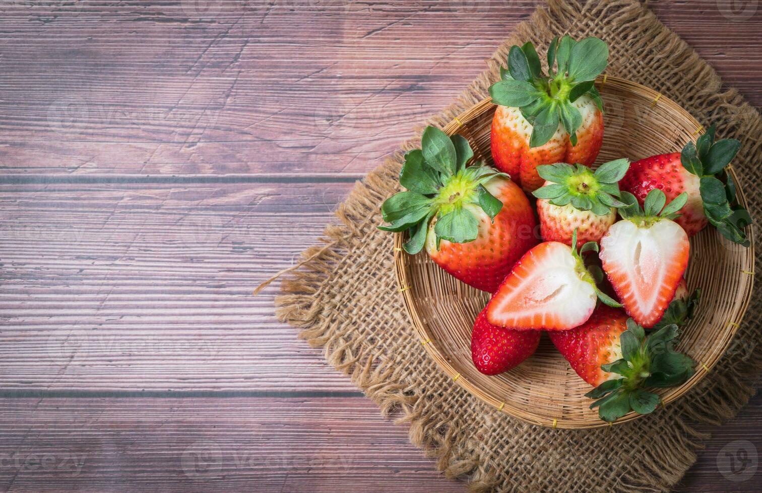 Frais tranché fraise dans bambou panier sur bois tableau, photo