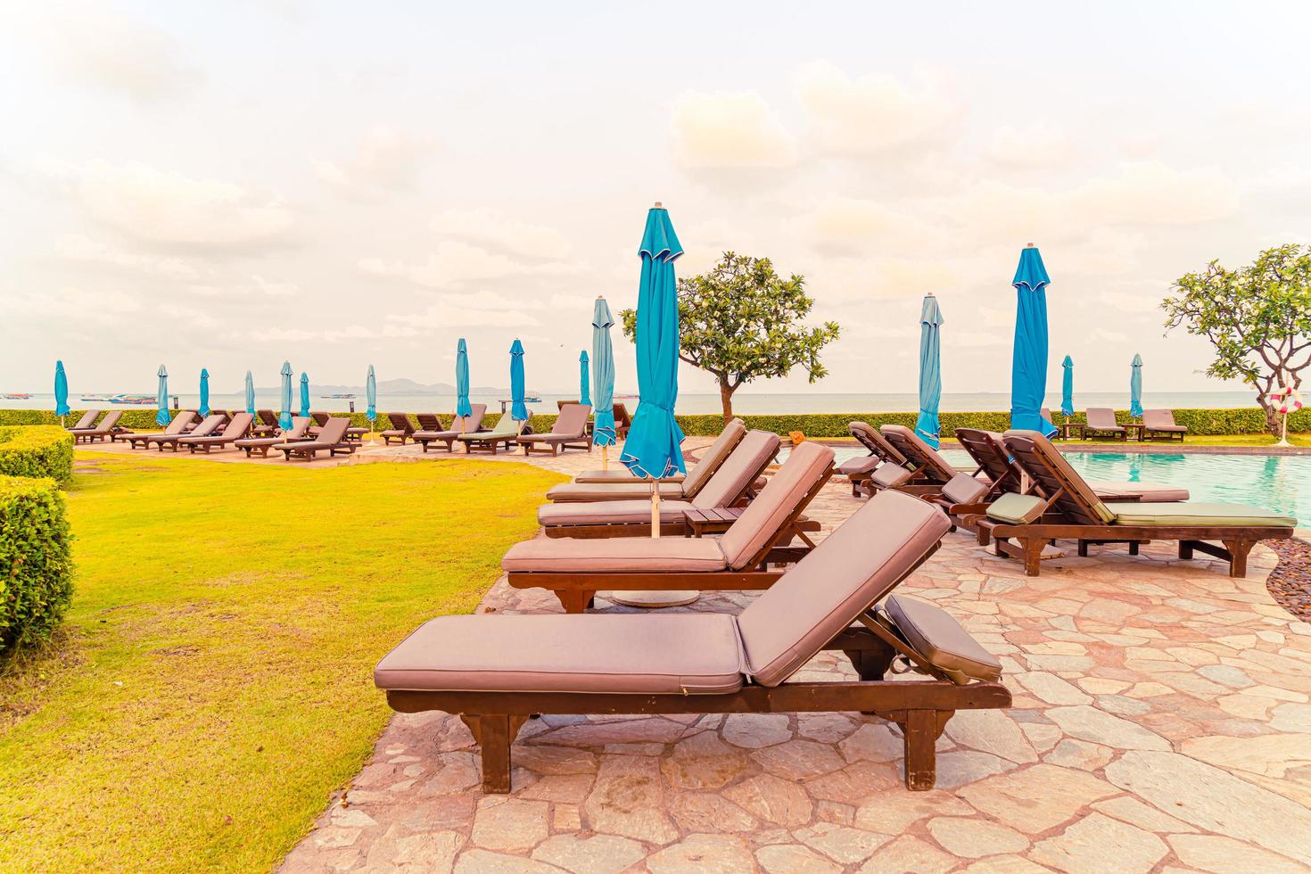 chaises de plage et piscine avec un fond de plage au coucher du soleil à pattaya, thaïlande photo