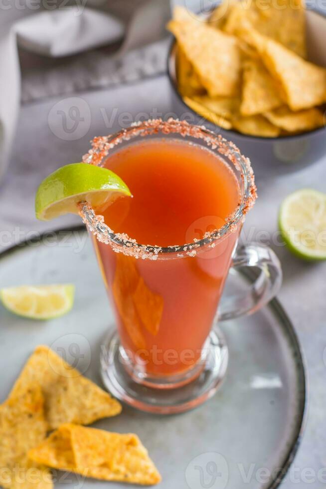 michelagua mocktail avec tomate jus et citron vert jus dans une verre et Nachos dans une bol verticale vue photo