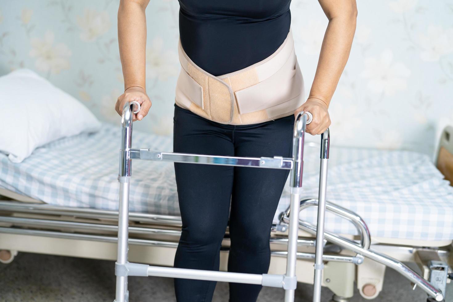 Patiente asiatique portant une ceinture de soutien de la douleur dorsale pour lombaire orthopédique avec marcheur photo
