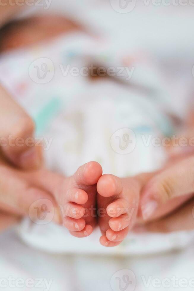 nouveau née bébé pieds sur blanc couverture. mère tenir pieds de nouveau née bébé. maternité et petite enfance concept. photo