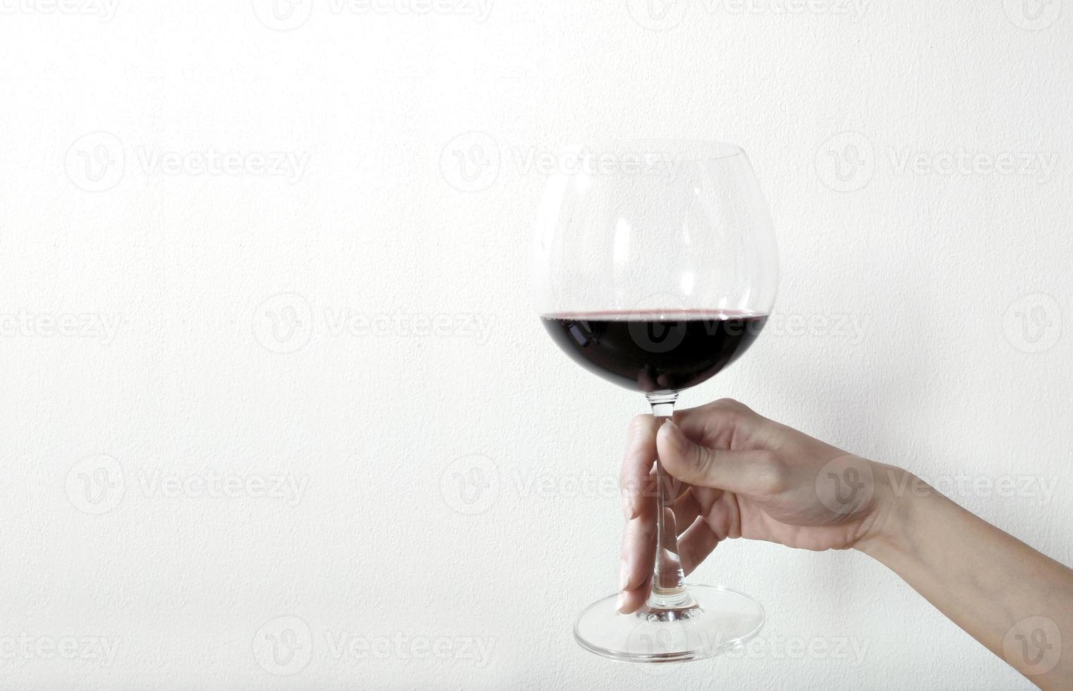 Main de femme avec un verre de vin sur fond blanc photo