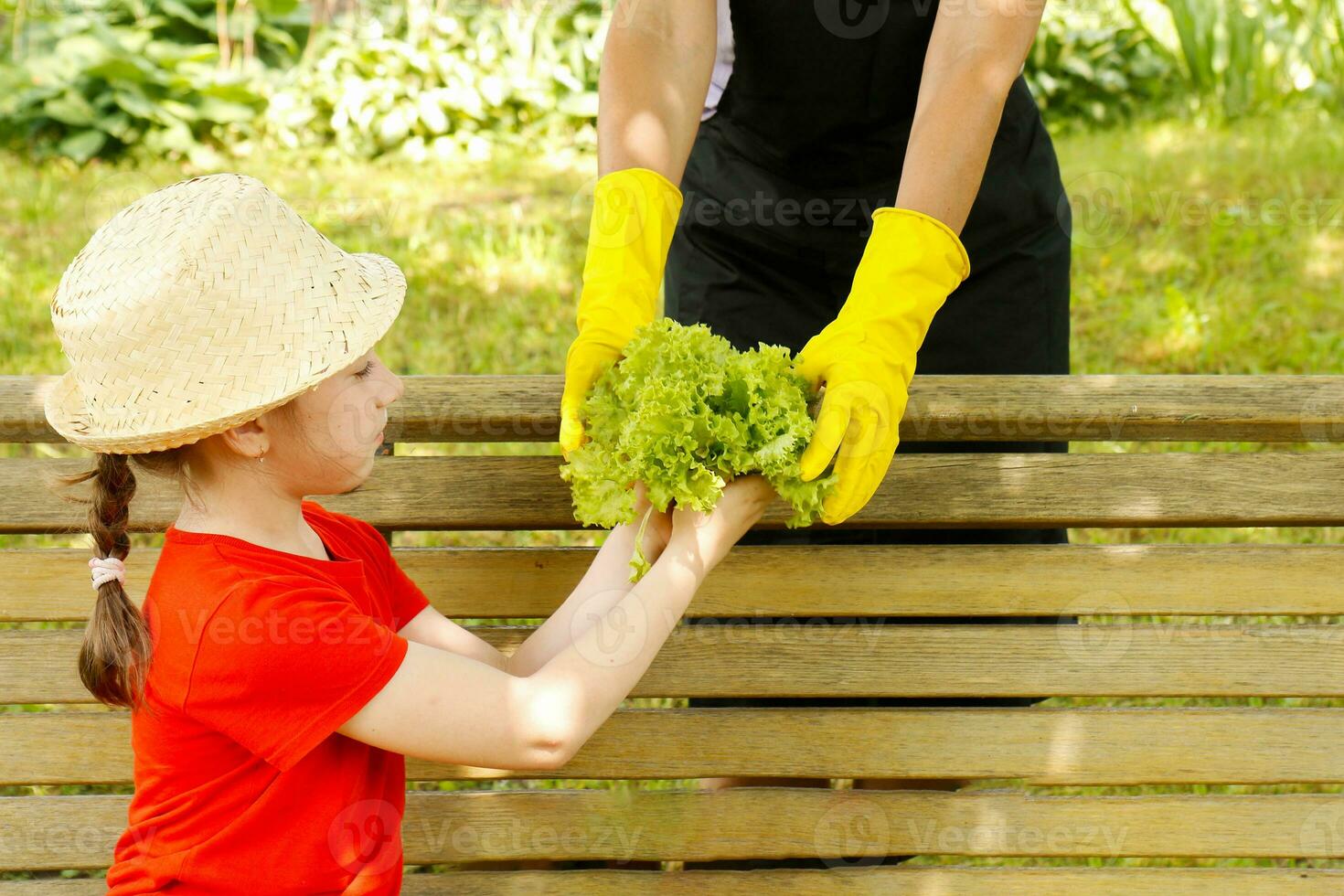 maman donne sa mignonne fille dans une paille chapeau juste une déchiré bouquet de verdure photo