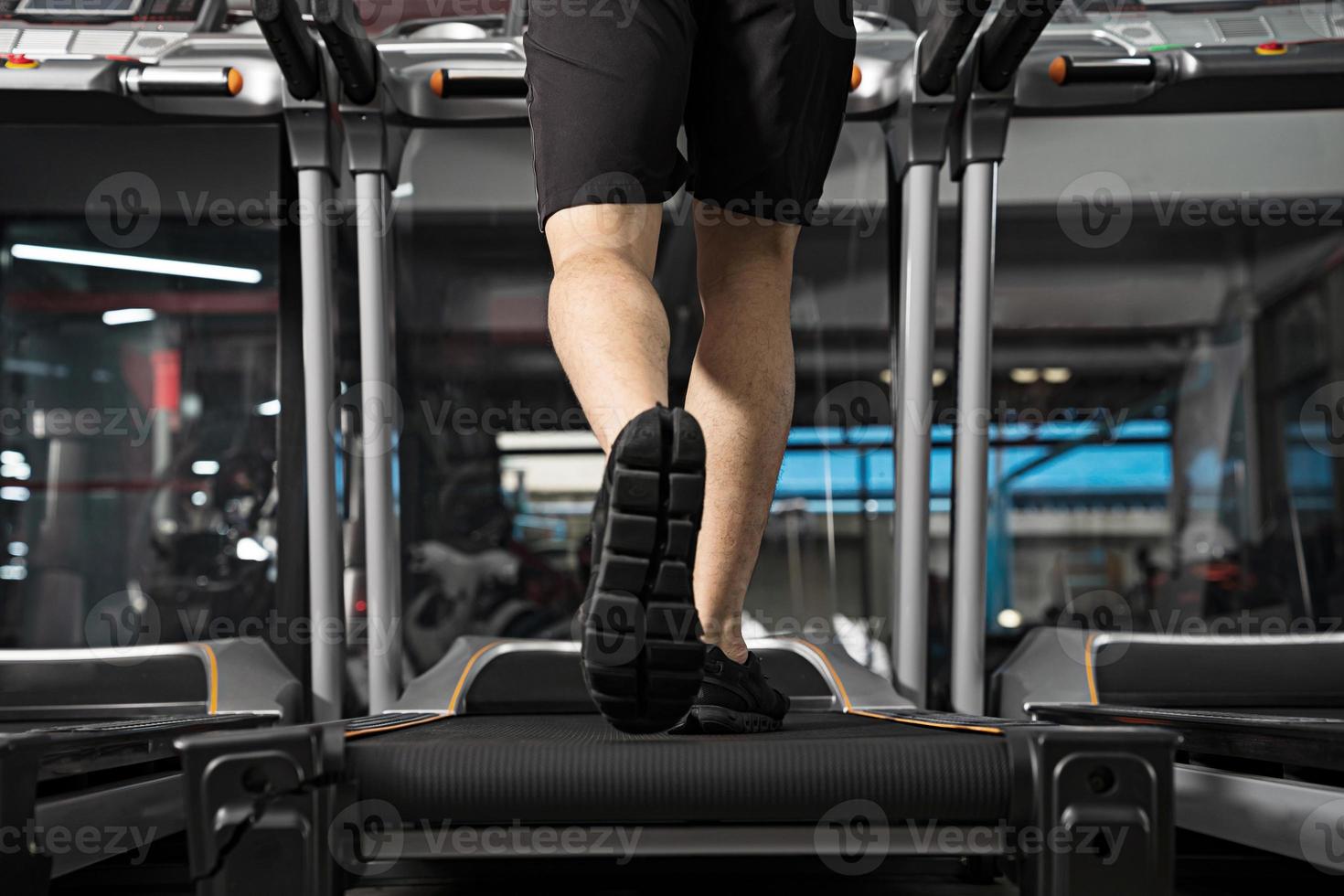 Close up of male jambes s'exécutant sur tapis roulant dans la salle de sport photo