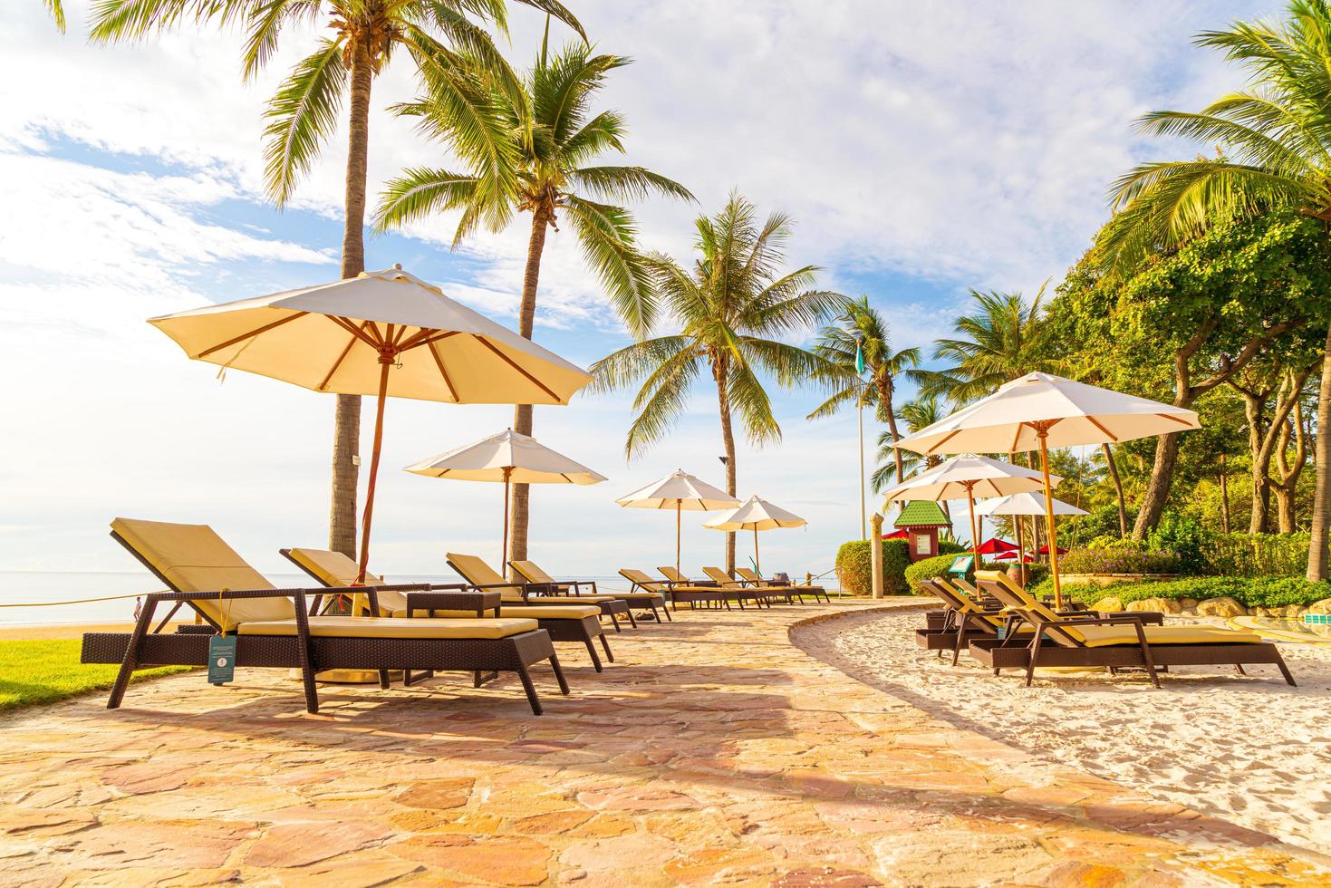 beau parasol et chaise de luxe autour de la piscine extérieure de l'hôtel et du complexe avec cocotier au coucher du soleil ou au lever du soleil photo