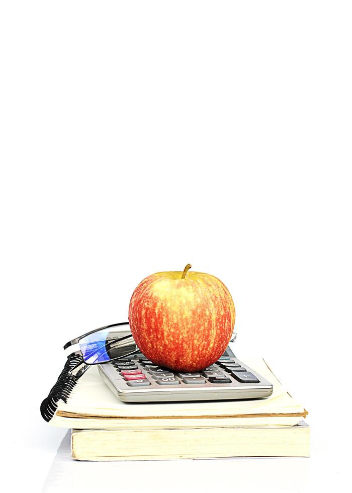 pomme rouge sur pile de livres et calculatrice avec lunettes photo