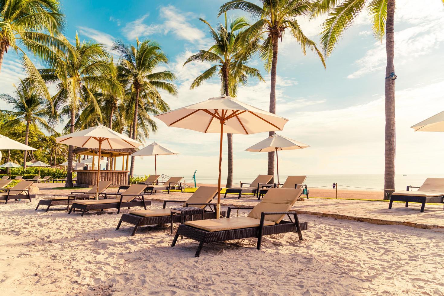 beau parasol et chaise de luxe autour de la piscine extérieure de l'hôtel et du complexe avec cocotier au coucher du soleil ou au lever du soleil photo