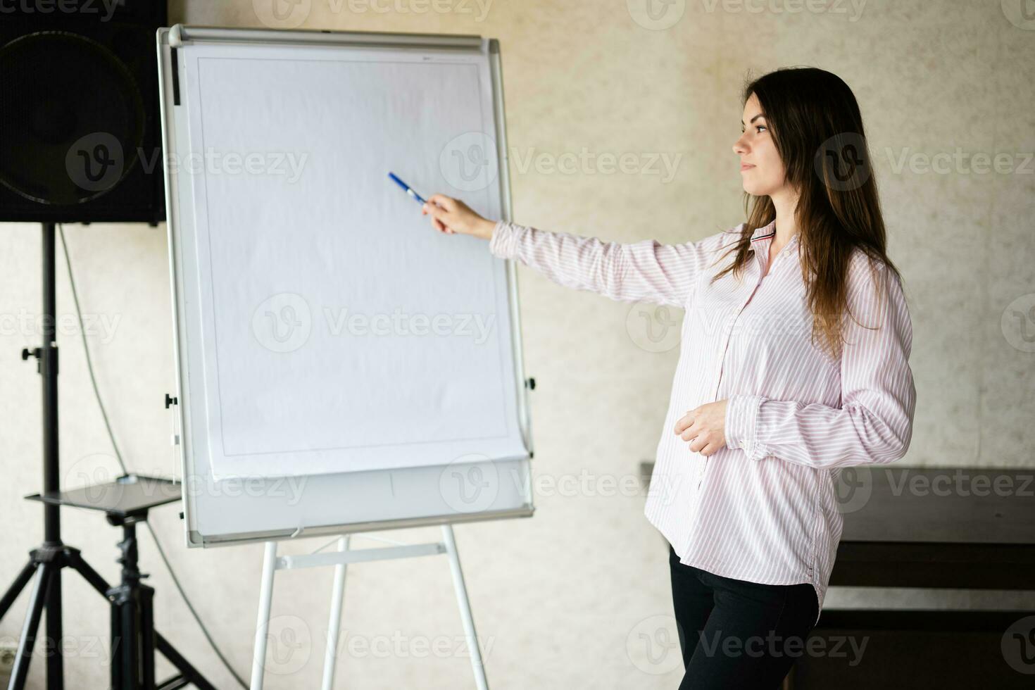 concentré Jeune caucasien orateur femme entraîneur spectacle sur blanc conseil, en train de préparer ou donnant éducatif conférence. femelle équipe chef expliquant projet idées. photo