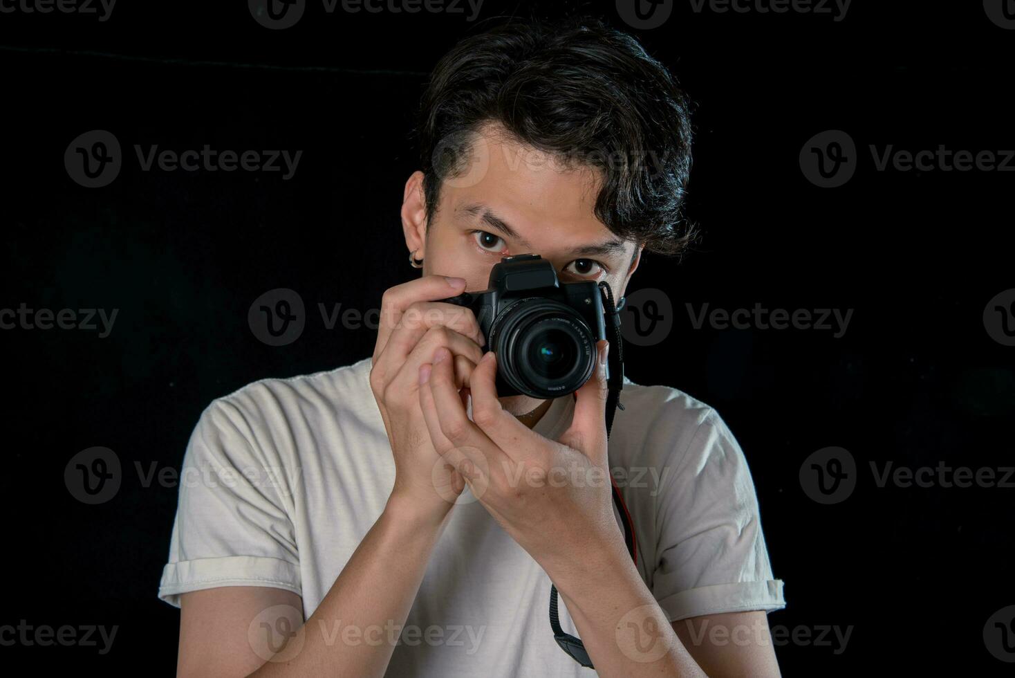 portrait de Hommes en portant une dslr à la recherche caméra sur foncé studio Contexte , asiatique photo