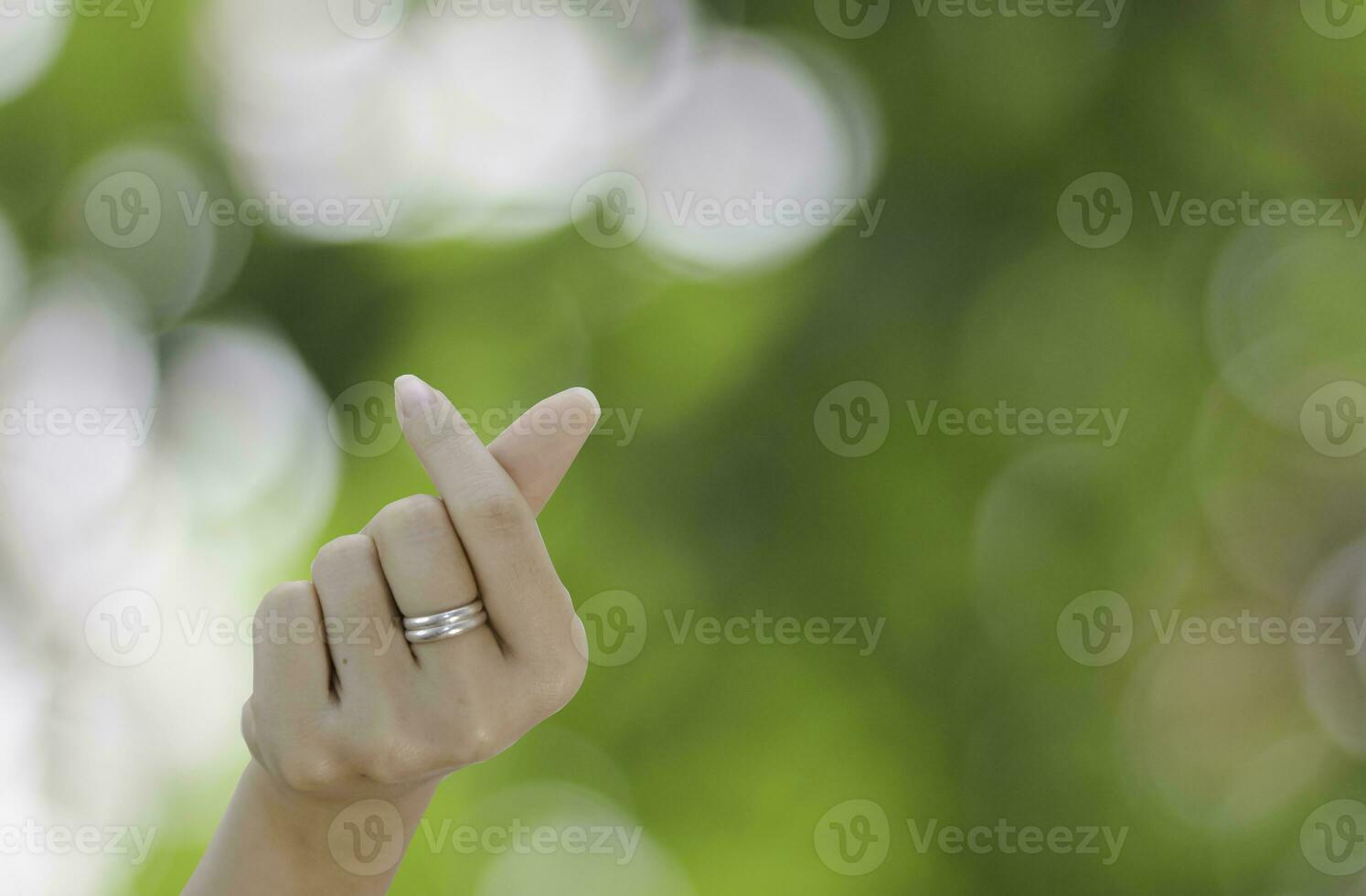 magnifique mini cœur de gril montrant l'amour doigt forme cœur fermer sur vert bokeh Contexte photo