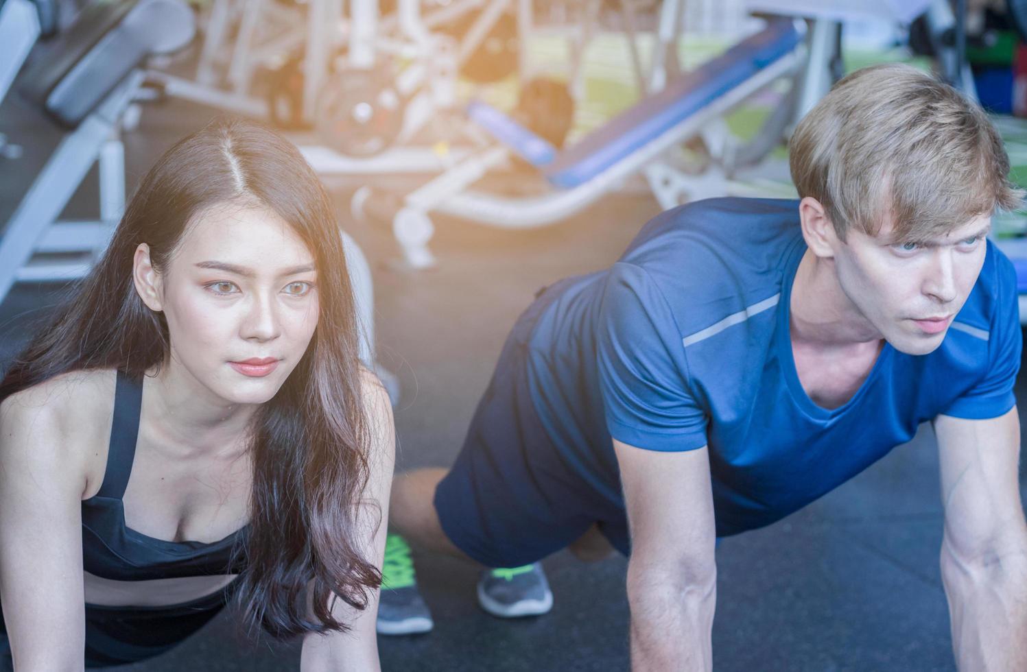 belle femme asiatique fait de l'exercice dans une salle de sport avec un entraîneur personnel concept de remise en forme bel homme pour la santé photo
