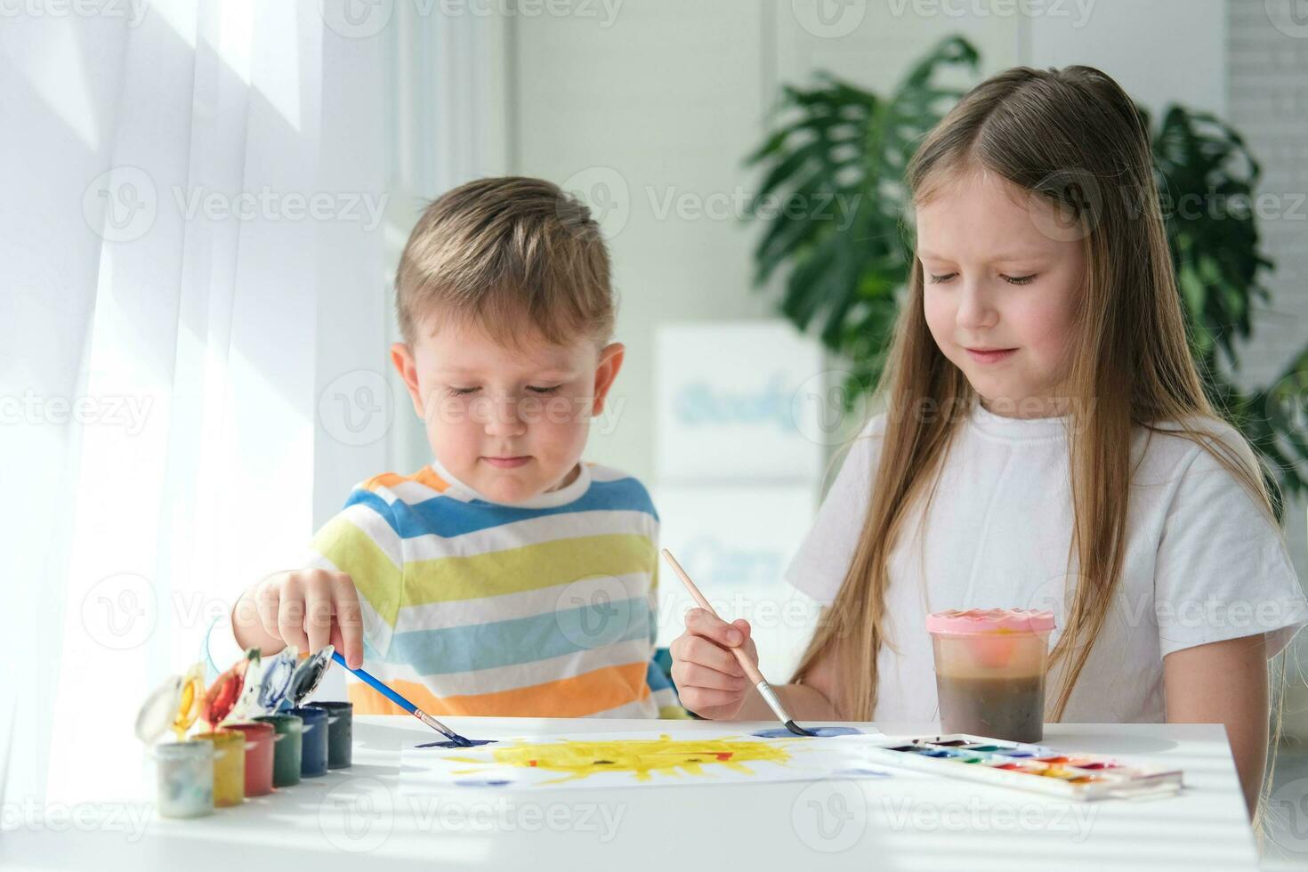 frère et sœur dessiner une image avec des peintures sur une pièce de papier. les enfants sont apprentissage à dessiner. Accueil la créativité. photo