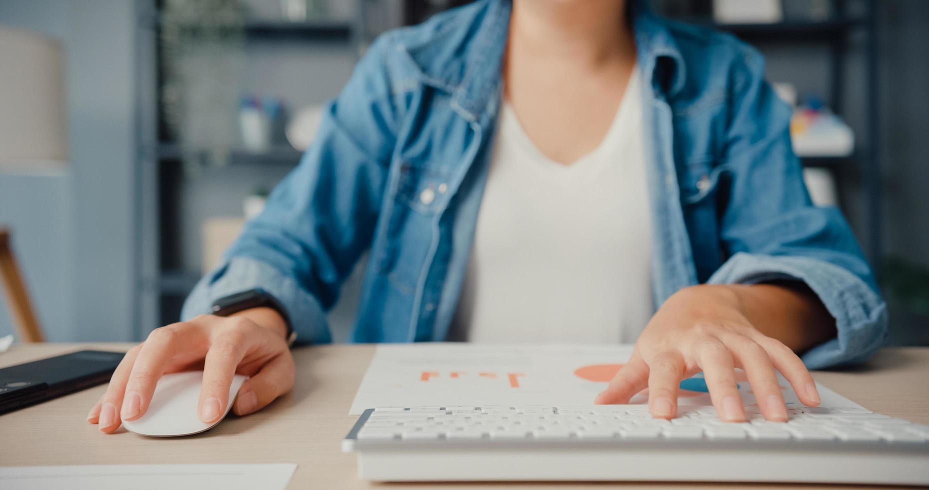 femme asiatique indépendante vêtements décontractés à l'aide d'un ordinateur de bureau en ligne apprendre dans le salon à la maison photo