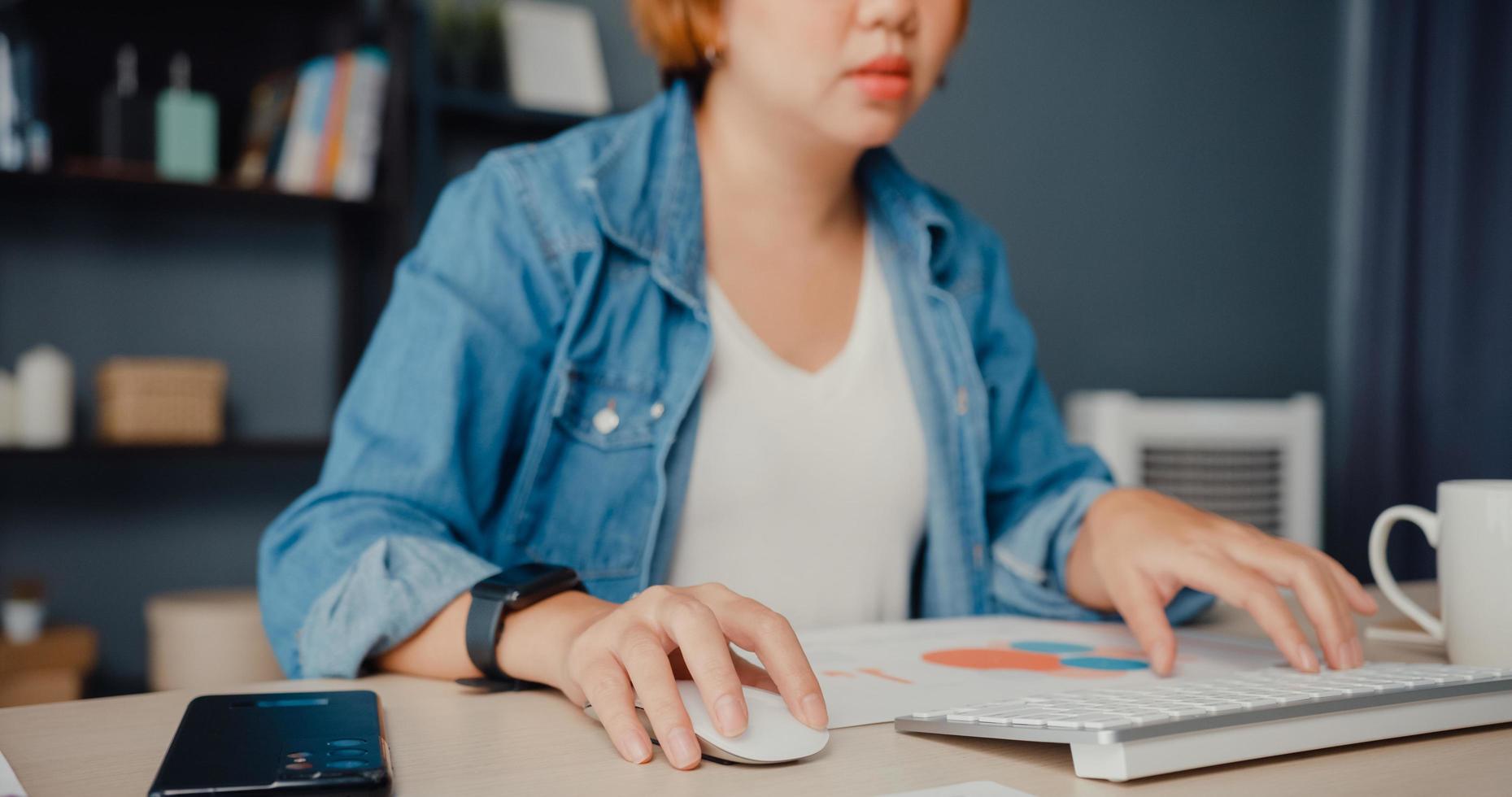 femme asiatique indépendante vêtements décontractés à l'aide d'un ordinateur de bureau en ligne apprendre dans le salon à la maison photo