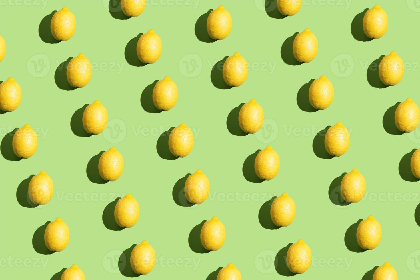 motif répétitif de style pop art coloré fait de citrons avec une ombre dure sur fond vert photo