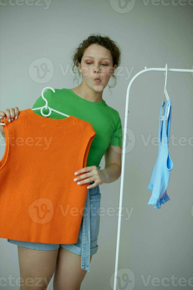 portrait de une Jeune femme vert t-shirts près vêtements cintres isolé arrière-plans inchangé photo