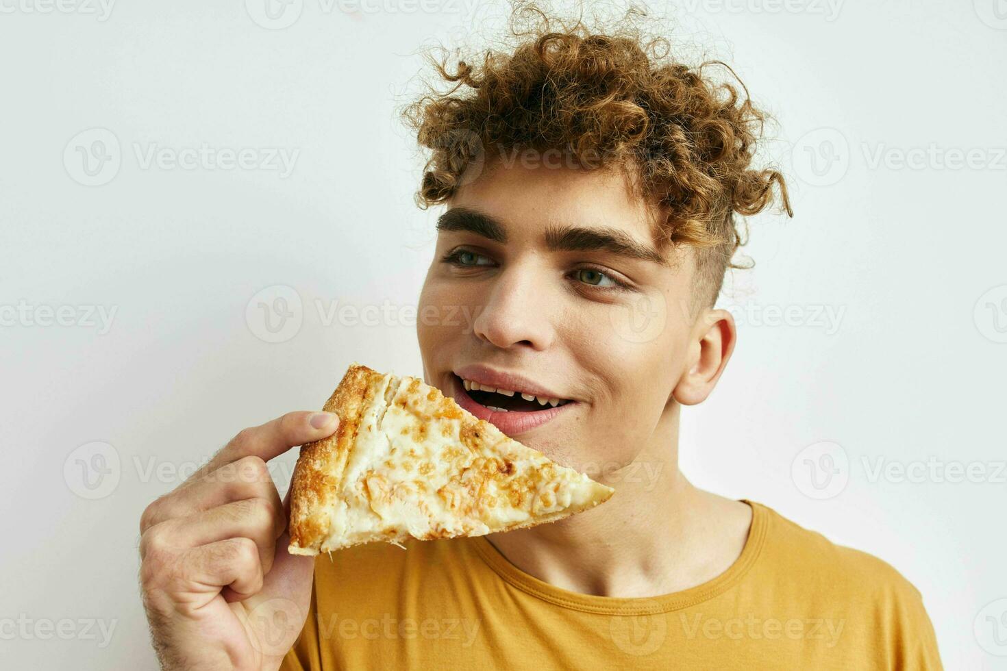 Beau gars en mangeant Pizza posant fermer lumière Contexte photo