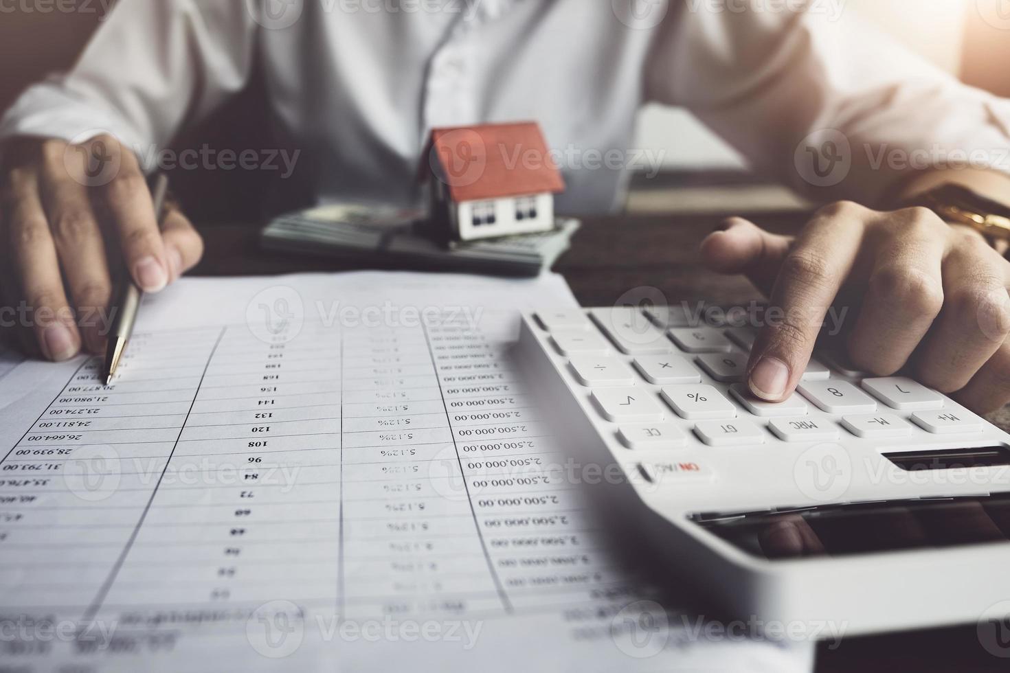 le client utilise un stylo et une calculatrice pour calculer le prêt pour l'achat d'une maison photo