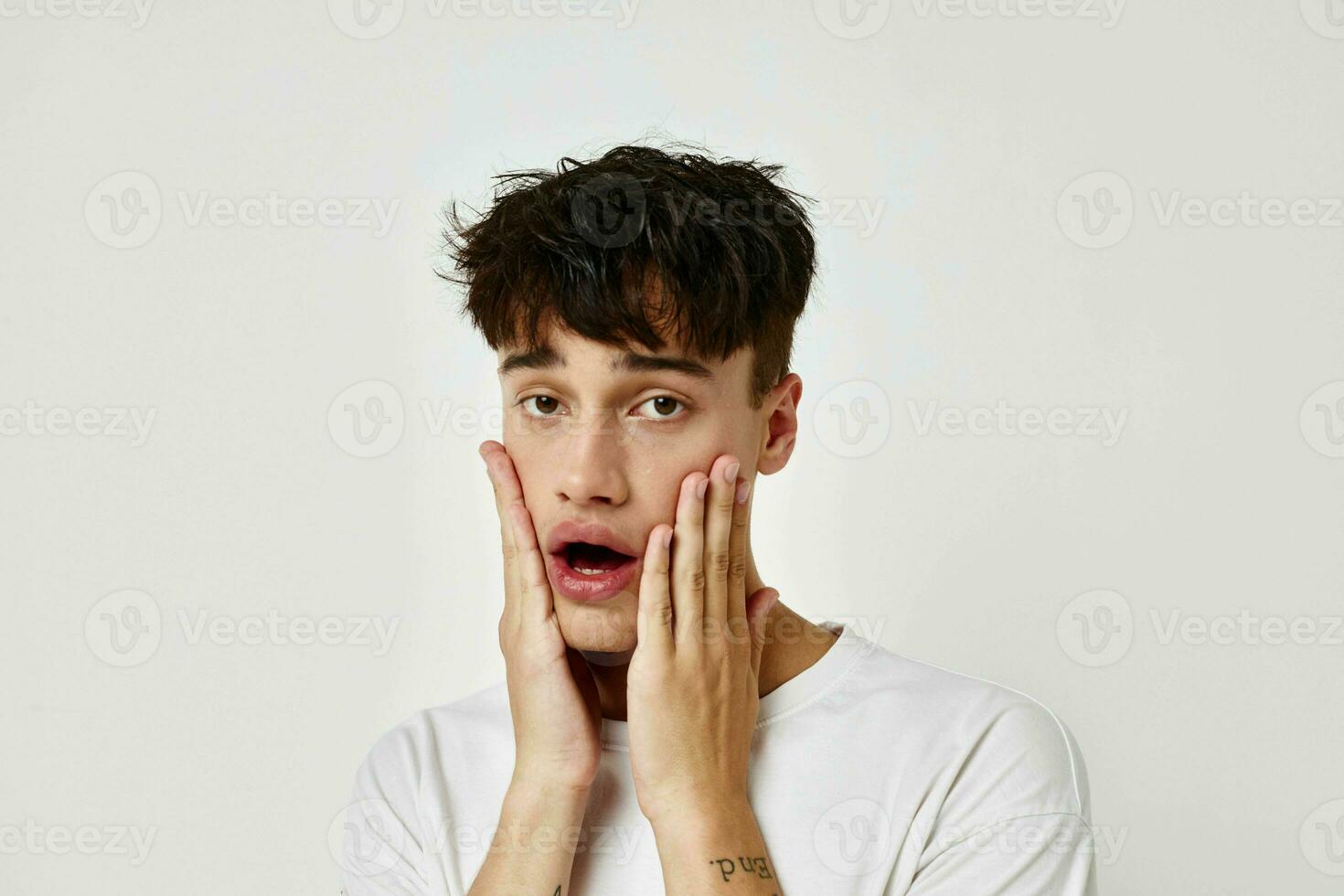 une Jeune homme tatouage sur mains dans blanc T-shirt lumière Contexte inchangé photo