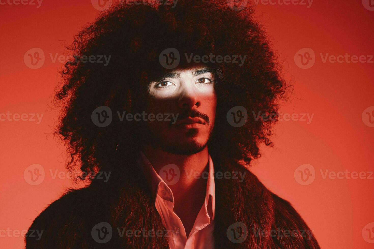 mode portrait de une homme avec frisé cheveux sur une rouge arrière-plan, multinational, coloré lumière, branché, moderne concept. photo