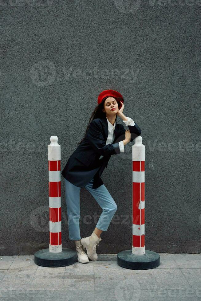 mode femme permanent sur le rue dans de face de le ville et route travaux touristique dans élégant vêtements avec rouge lèvres et rouge béret, voyage, cinématique couleur, rétro ancien style, Urbain mode. photo