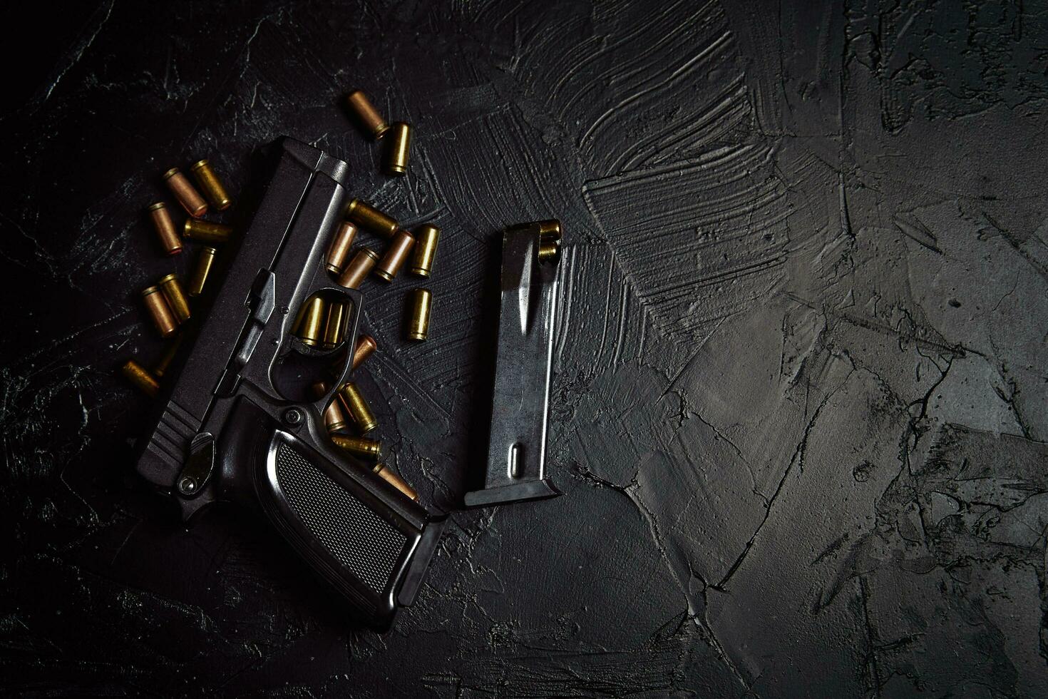 pistolet avec cartouches sur table en béton noir photo