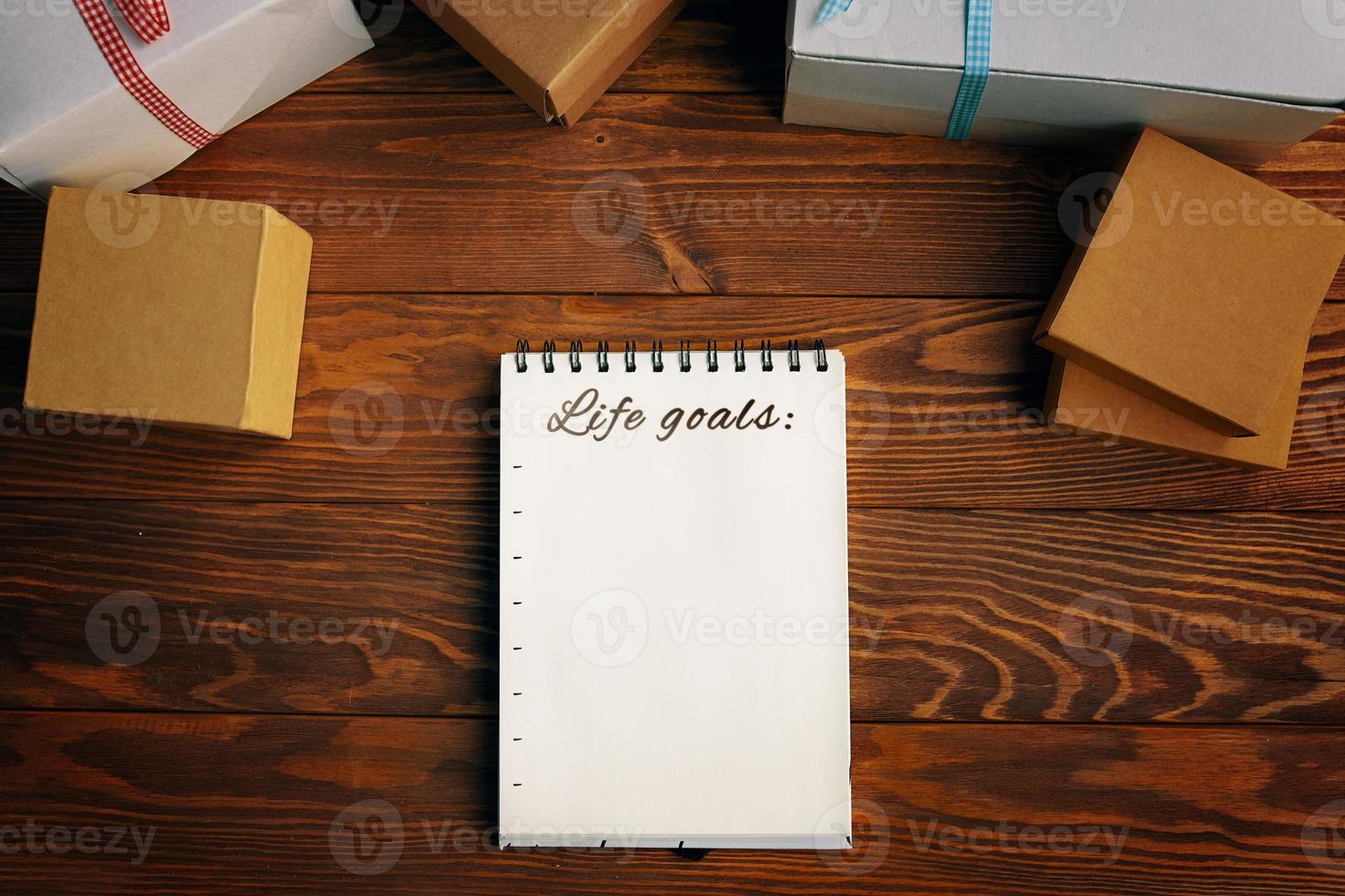 table en bois avec des coffrets cadeaux bloc-notes avec liste d'objectifs de vie photo