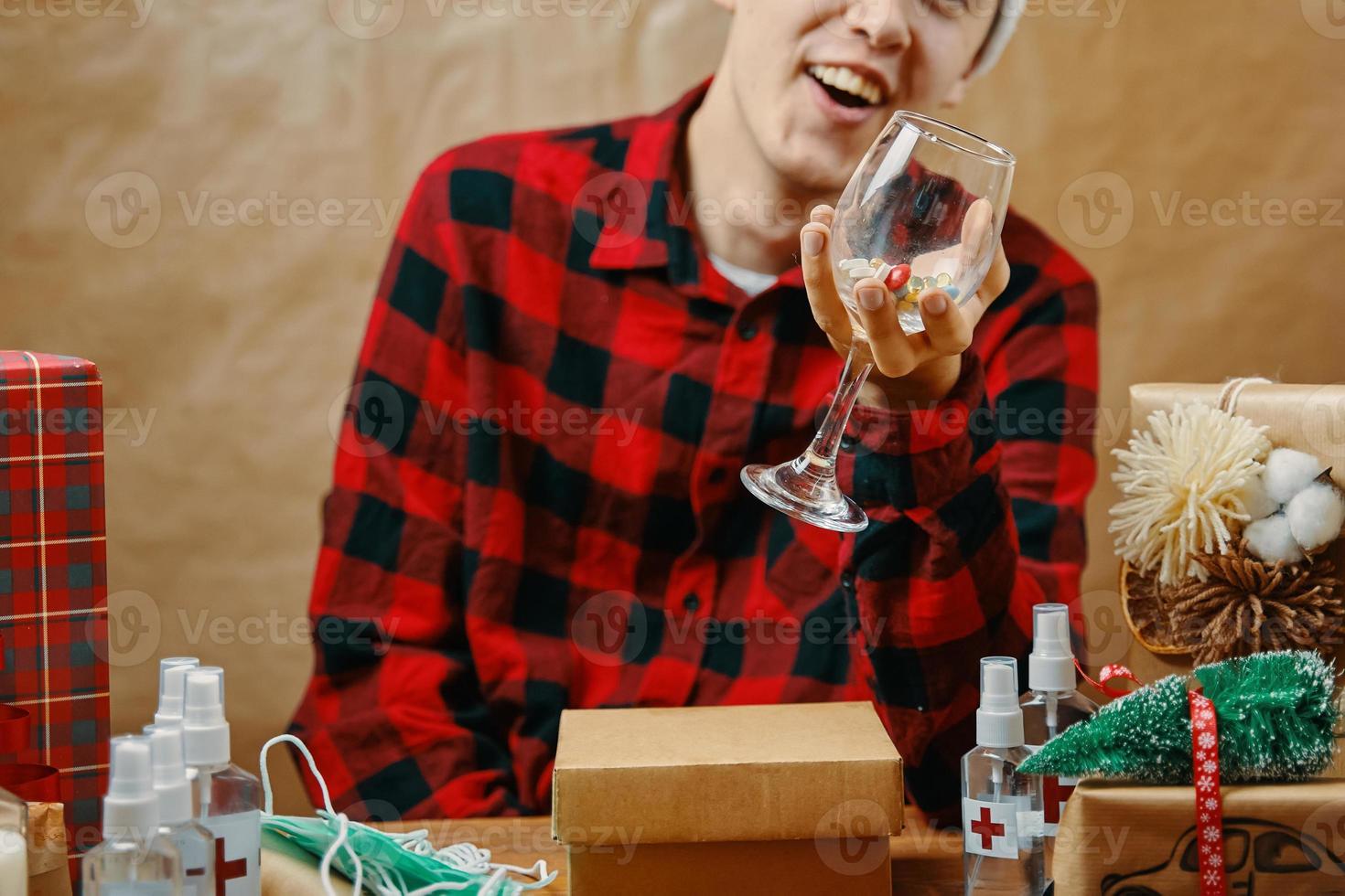 un gars en chemise à carreaux tient un verre avec des médicaments et des pilules photo