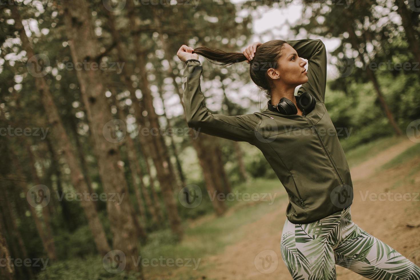 Jeune belle coureuse écoutant de la musique et prenant une pause après le jogging dans une forêt photo