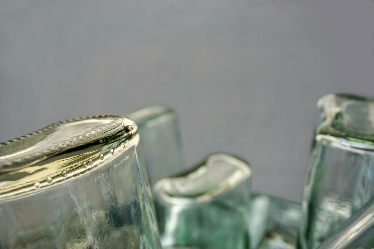 fermer et surgir de en haut côté vers le bas et bas de plat verre bouteille sur flou gris Contexte. photo