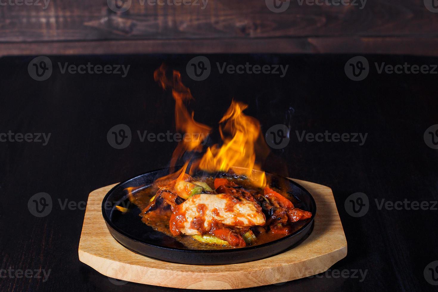 fajitos, viande dans une poêle à frire avec feu sur un plateau en bois, belle portion, fond sombre photo