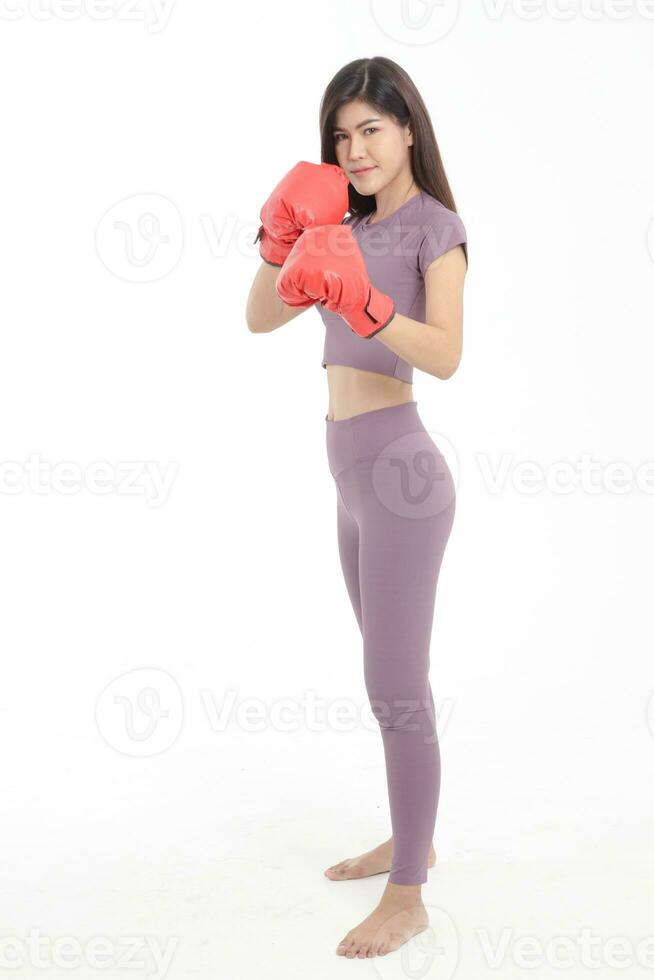 magnifique asiatique femme avec bien figure portant violet faire des exercices vêtements avec rouge boxe gants permanent sur une blanc Contexte. aptitude concept poids perte, en bonne santé santé se soucier. photo