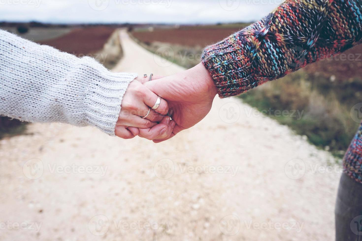 Libre d'un jeune couple se tenant la main montrant leur engagement dans un voyage d'aventure sur un chemin de campagne en plein air comme profondeur de champ photo