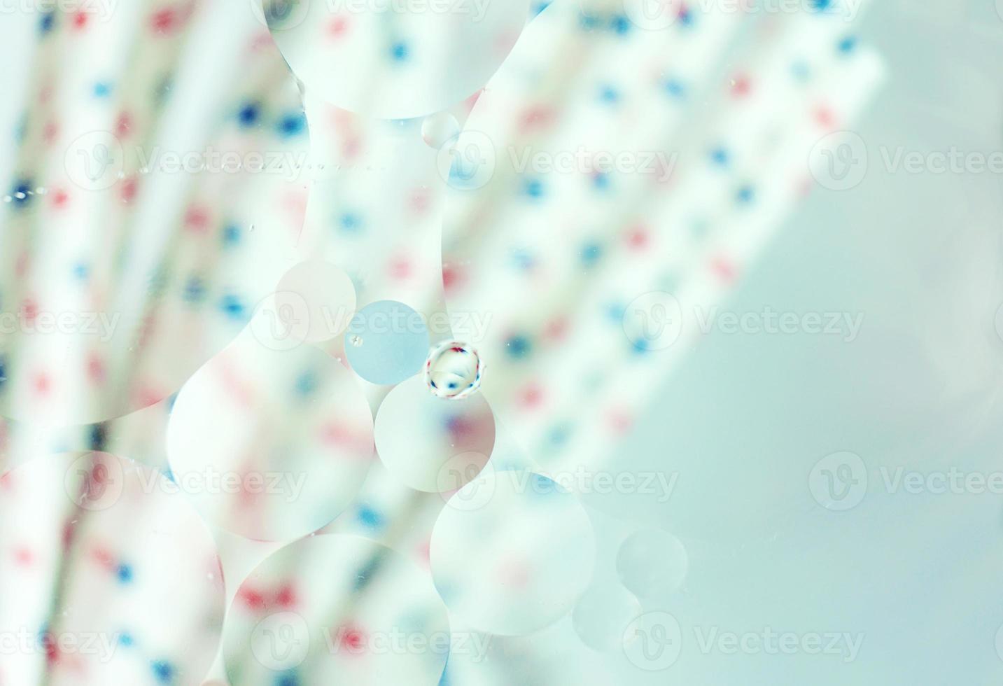 une belle macro colorée de bulles d'huile sur l'eau avec un flou de points rouges et bleus sur des pailles blanches en arrière-plan avec filtre vintage photo