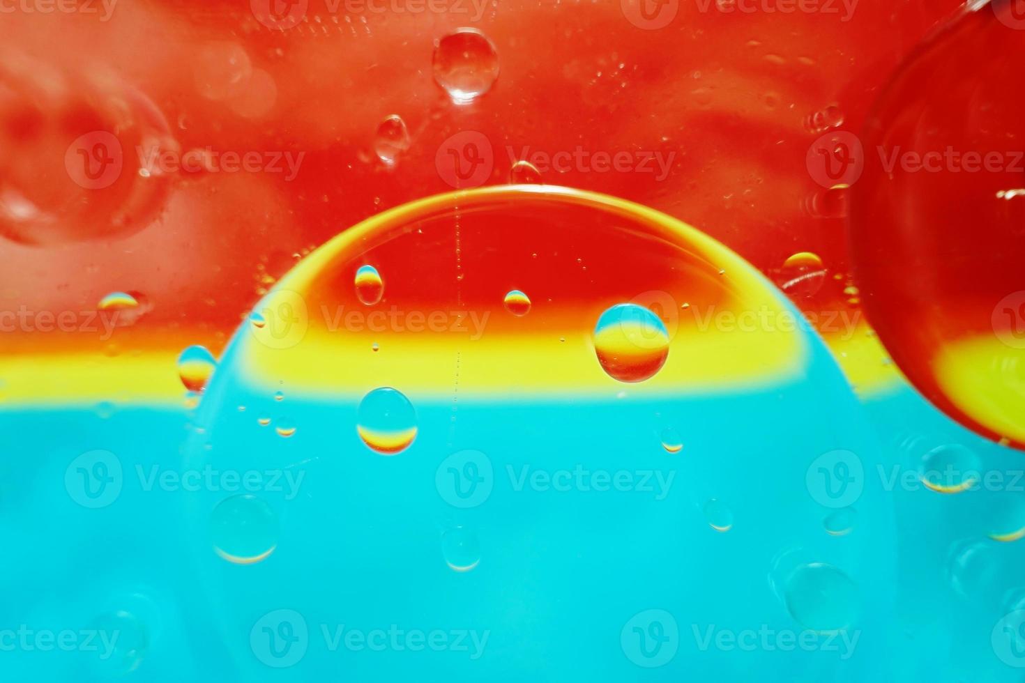 une belle et vibrante macro de bulles d'huile sur l'eau avec une texture à rayures jaunes, bleues et rouges comme motif de fond avec filtre vintage photo