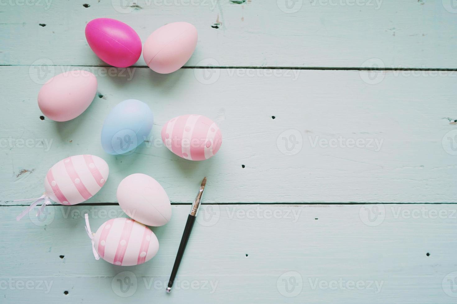 un beau gros plan coloré d'œufs de pâques isolés dans des couleurs unies et rayé par un petit pinceau sur une table en bois bleu pastel avec de l'espace photo