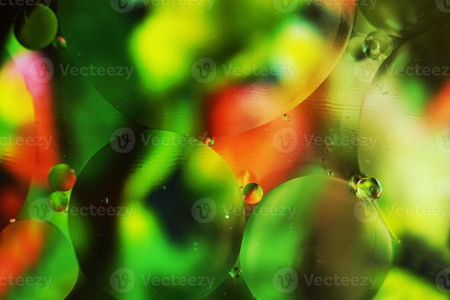 une belle macro colorée de bulles d'huile sur l'eau avec une texture florale verte, rouge et noire comme motif de fond avec un filtre vintage photo