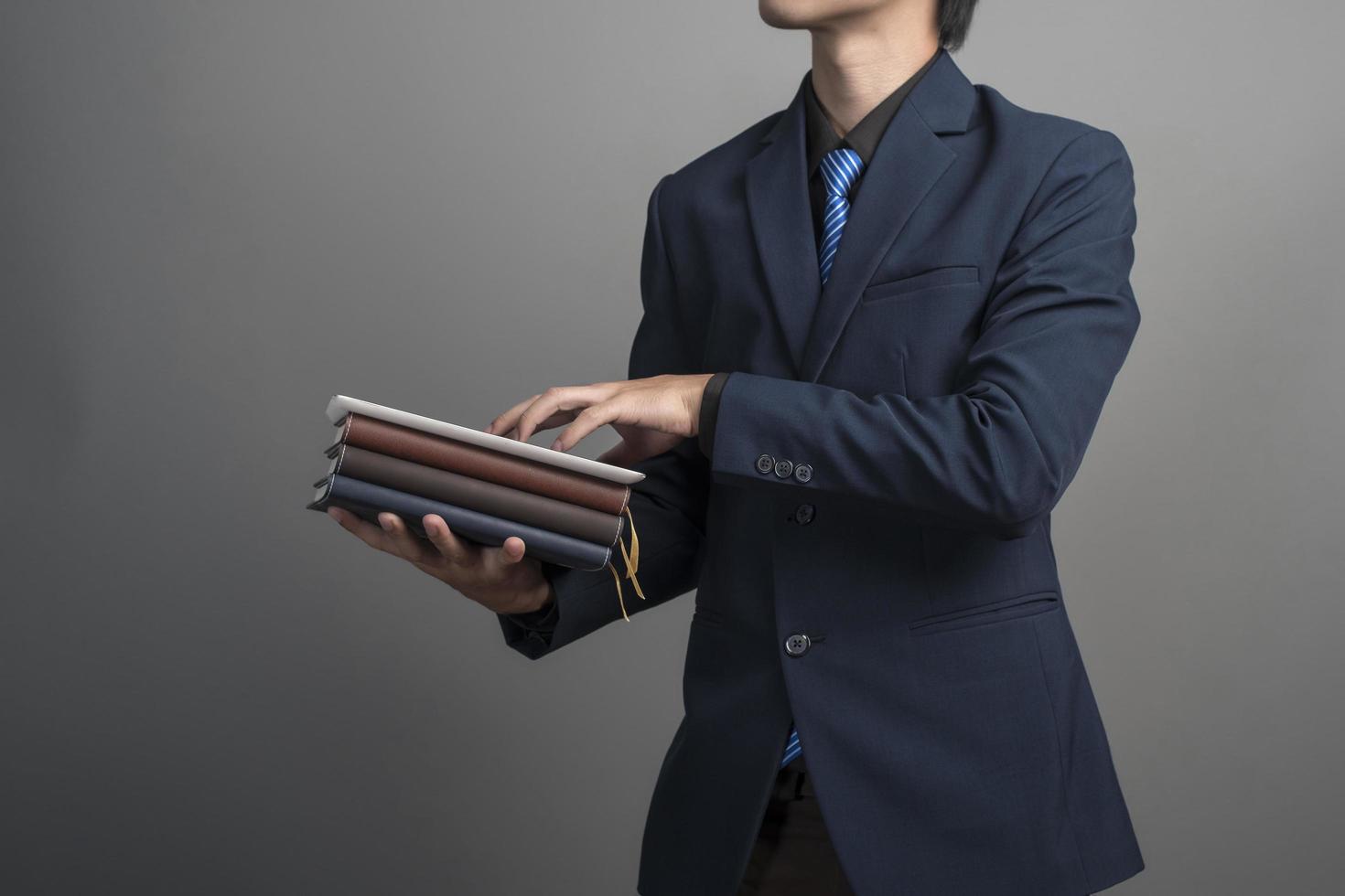 Close up of businessman in blue suit holding books sur fond gris photo