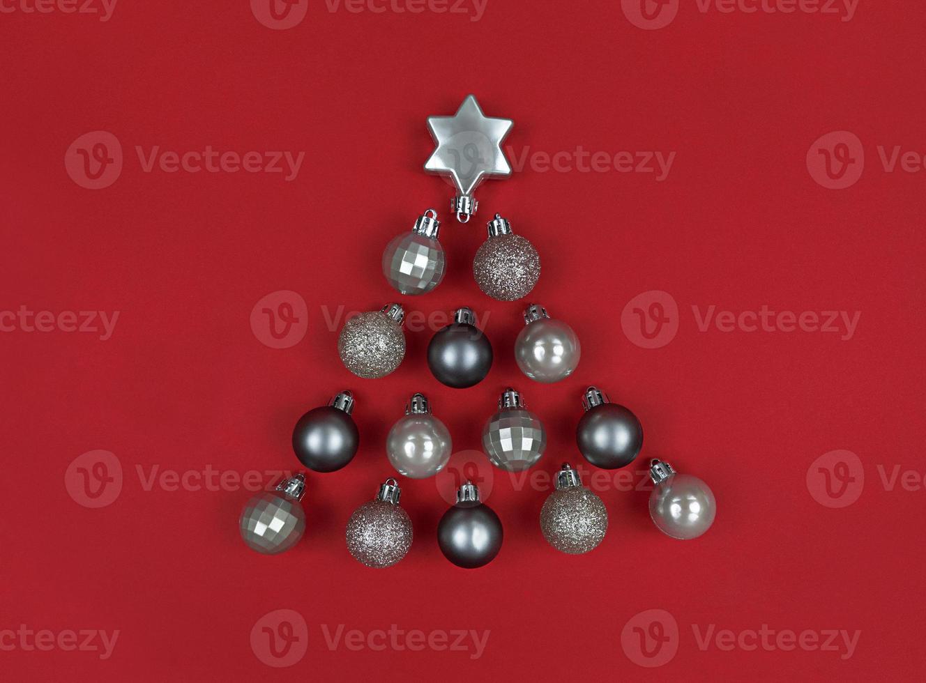 forme d'arbre de noël fait avec des boules de décoration sur un papier rouge. photo