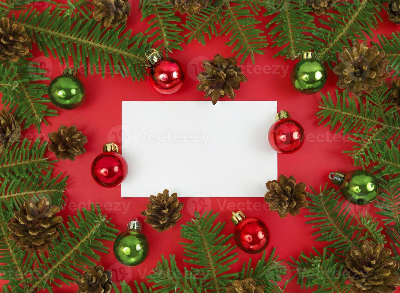 carte postale de vacances avec des branches de sapin, des cônes et des boules sur fond rouge. mise à plat de noël avec espace de copie. photo