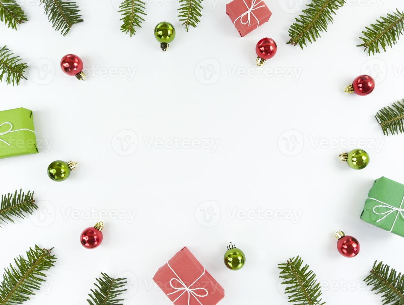 plat de noël avec espace de copie au milieu. carte postale de vacances avec branches de sapin, boules vertes et rouges, coffrets cadeaux sur fond blanc. photo