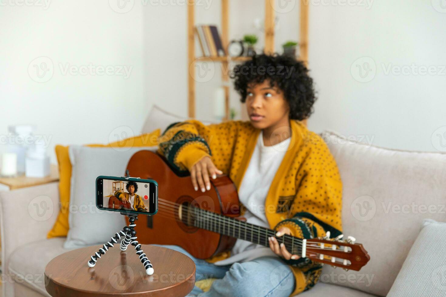 blogueur guitariste. africain américain fille blogueur en jouant guitare parlant à webcam enregistrement vlog. social médias influenceur femme diffusion à Accueil à l'intérieur. la musique contenu créateur diffuser Didacticiel. photo