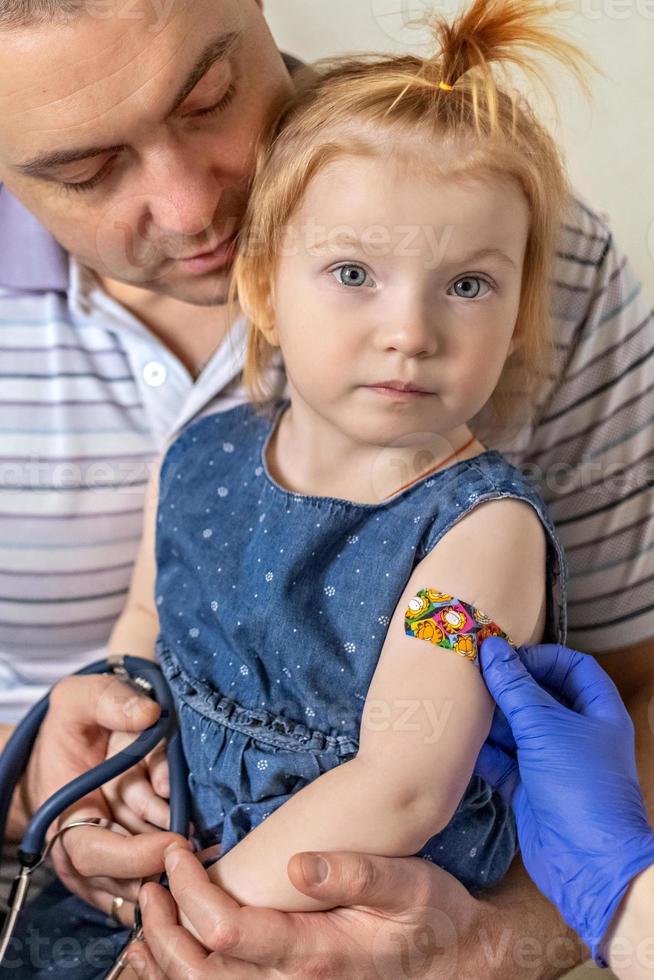 une petite fille avec son père dans le cabinet du médecin de la clinique se fait vacciner contre le coronavirus.le concept de vaccination, immunisation, prévention contre covid-19. photo