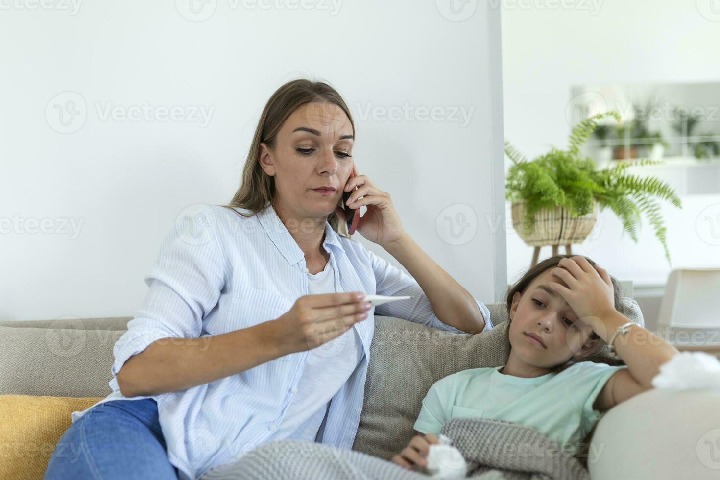 mère mesurant la température de son enfant malade. enfant malade avec une forte fièvre couché dans son lit et mère tenant un thermomètre. mère avec téléphone portable appelant au médecin photo