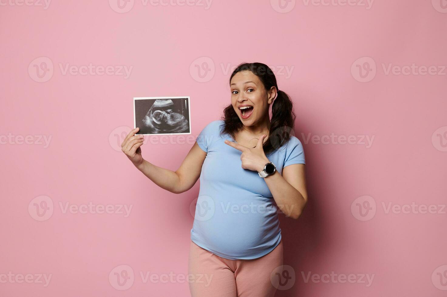 fou de joie charmant Enceinte femme points de côté le ultrason analyse image de sa futur bébé, isolé sur rose arrière-plan, photo