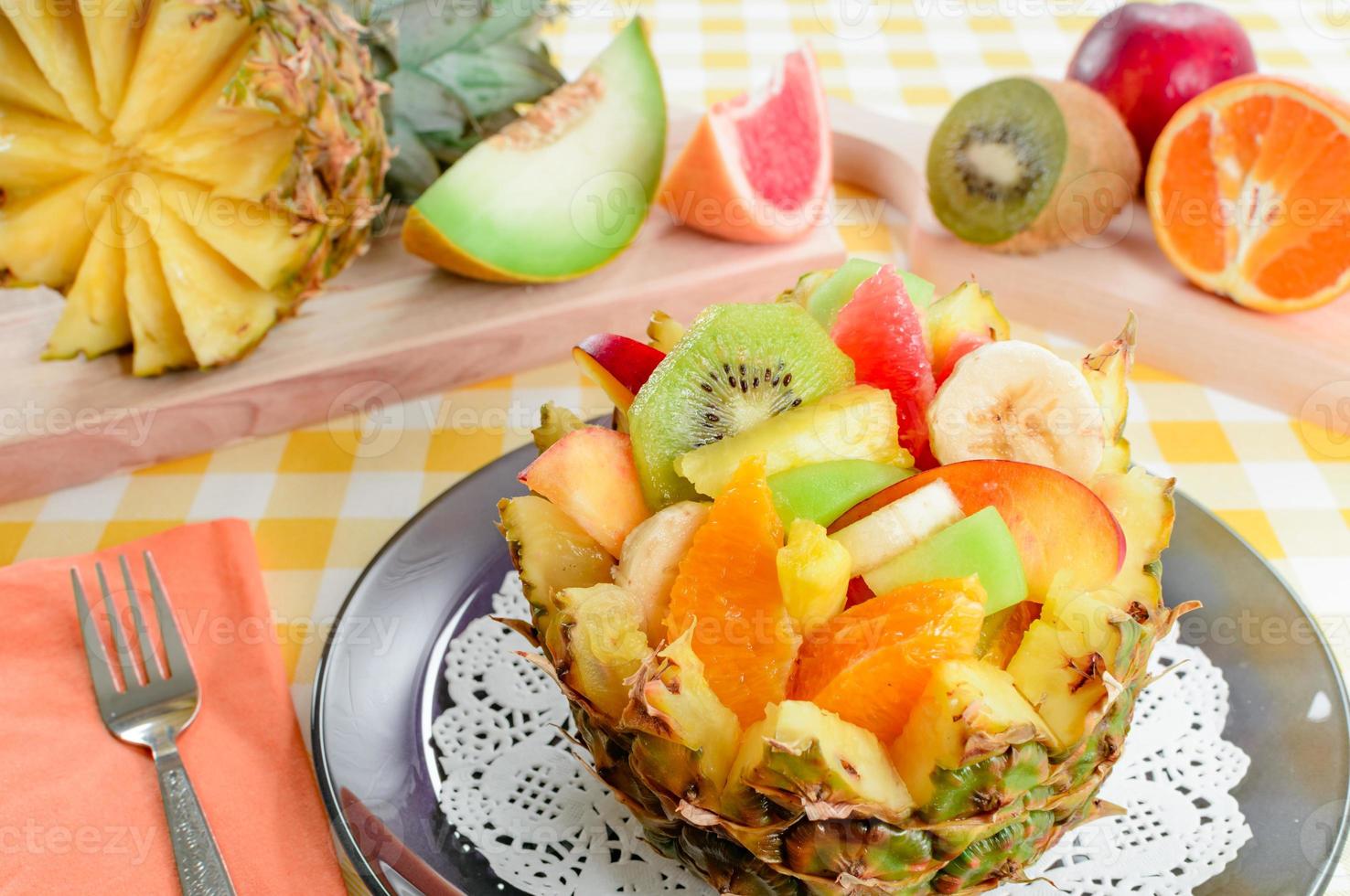 salade de fruits frais avec kiwi, banane, pêche, orange, orange rouge, abricot et melon dans un bol d'ananas fait à la main. photo