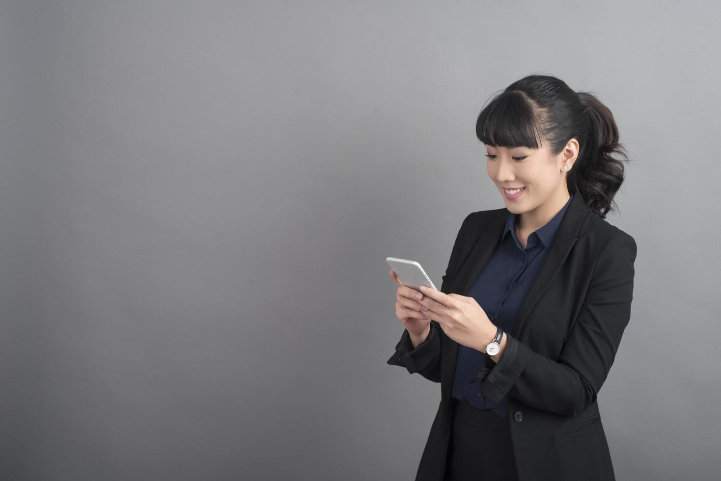 belle femme d'affaires à l'aide de smartphone sur fond gris photo