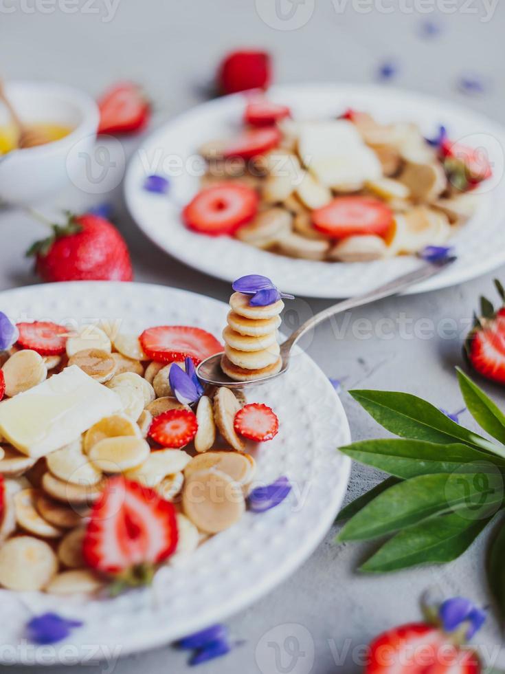 crêpes aux céréales, nourriture à la mode. mini crêpes aux céréales avec du beurre, du miel et des fraises. photo